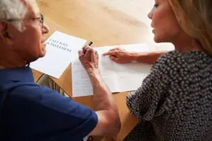 woman helping senior man to complete last will and testament